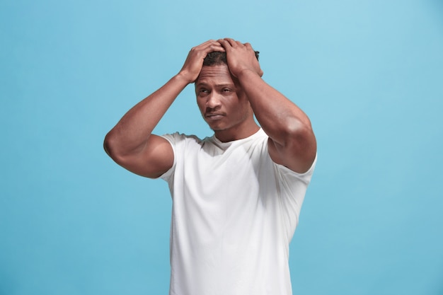 Homme afro-américain ayant des maux de tête. Isolé sur mur bleu