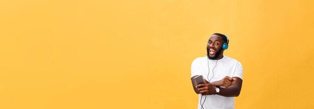 Un homme afro-américain avec un casque écoute et danse avec de la musique isolée sur fond jaune