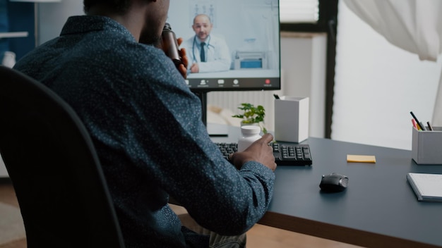 Photo gratuite homme afro-américain cherchant l'aide médicale d'un médecin via une consultation de télésanté internet en ligne avec un médecin de famille. bilan de santé par vidéoconférence virtuelle, patient cherchant des conseils médicaux