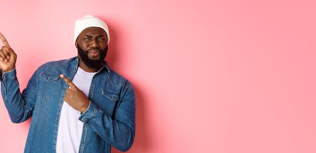 Photo gratuite homme afro-américain confus et déçu grimaçant pointant du doigt le coin supérieur gauche banne