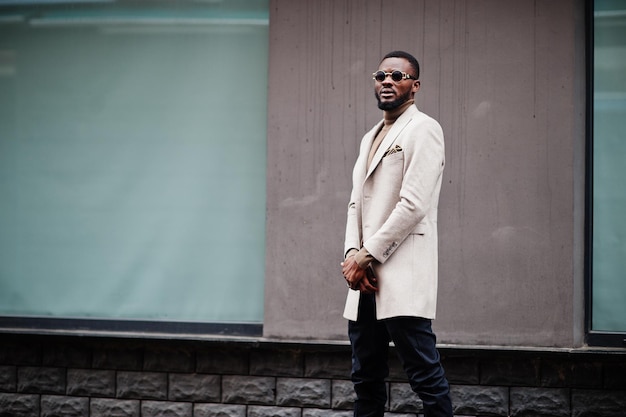 Un Homme Afro-américain élégant Porte Une Veste Beige Avec Des Lunettes De Soleil