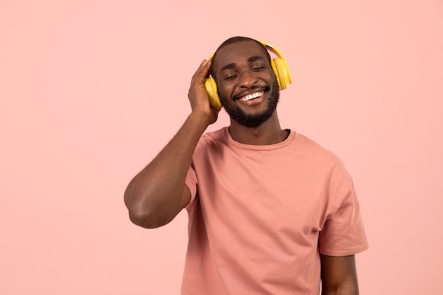 Homme afro-américain expressif écoutant de la musique sur des écouteurs