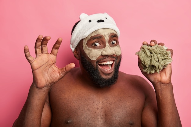 Photo gratuite homme afro-américain avec masque d'argile, exprime des émotions positives isolées