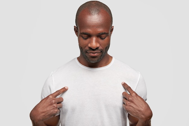 Homme afro-américain à la peau foncée indique au t-shirt blanc