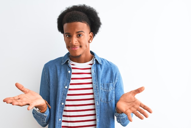 Photo gratuite homme afro-américain portant un t-shirt rayé et une veste en jean sur fond blanc isolé expression désemparée et confuse avec les bras et les mains levés concept de doute