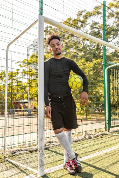 Homme afro-américain posant avec un ballon de football à l'extérieur