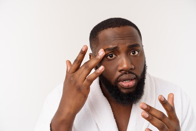 Homme afro-américain regarde les boutons sur le visage acné hygiène masculine isolé sur fond blanc studio