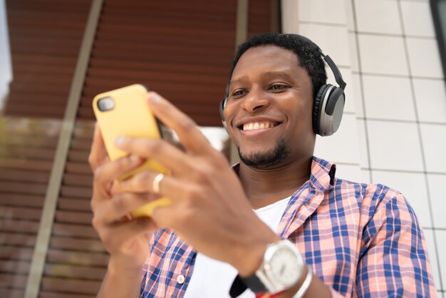 Homme afro-américain utilisant son téléphone portable tout en se tenant à l'extérieur dans la rue