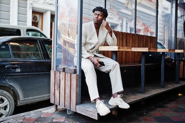 Photo gratuite homme afro élégant en costume beige old school assis à table dans la rue