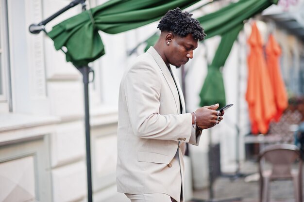 Photo gratuite homme afro élégant en costume beige old school avec téléphone portable