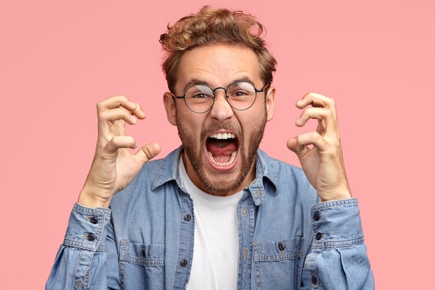 Photo gratuite un homme agacé agacé fait des gestes avec colère, exprime des émotions négatives, garde la bouche largement ouverte