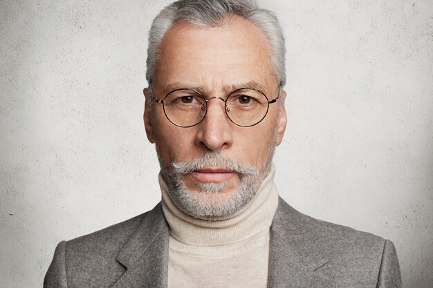 Homme âgé aux cheveux gris barbu habillé en costume formel