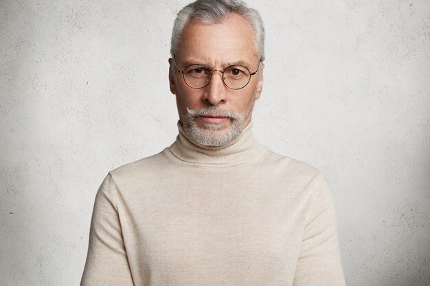 Homme âgé aux cheveux gris barbu portant un col roulé