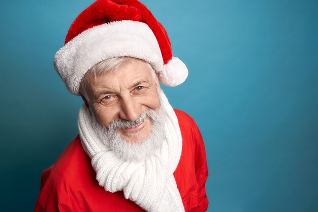 Homme âgé barbu en costume rouge de Noël et écharpe blanche