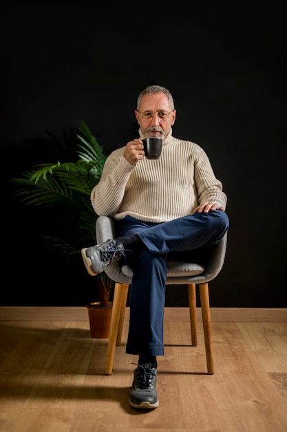 Photo gratuite un homme âgé avec une boisson chaude près d'une plante en pot