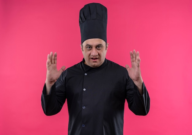 Photo gratuite homme d'âge moyen cuisinier en uniforme de chef montrant la taille sur un mur rose isolé