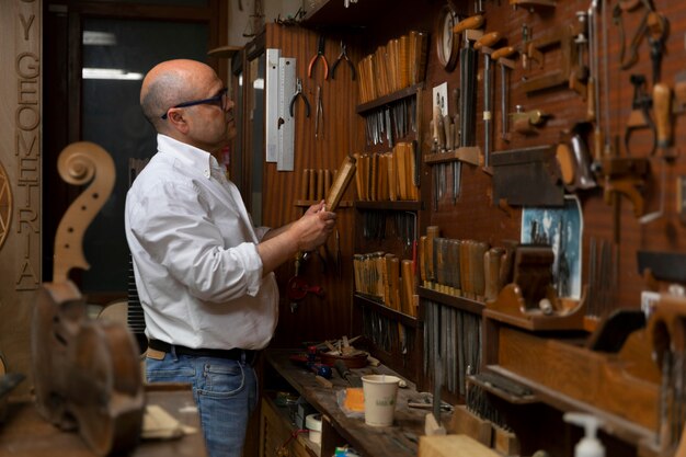 Homme d'âge moyen fabriquant des instruments dans son atelier seul