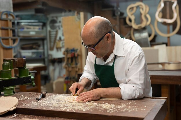 Homme d'âge moyen fabriquant des instruments dans son atelier seul