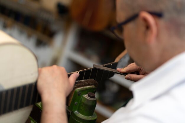 Homme d'âge moyen fabriquant des instruments dans son atelier seul