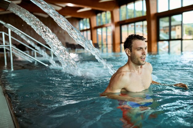 Homme d'âge moyen passant une journée au centre de bien-être et profitant d'une piscine