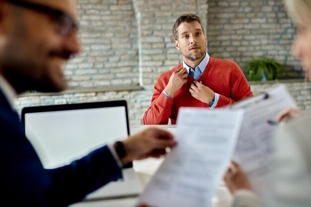 Homme d'âge moyen postulant à un emploi et attendant que l'équipe des ressources humaines examine son CV au bureau