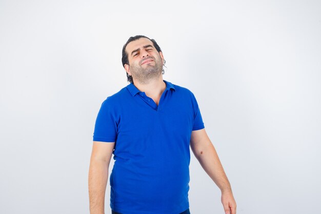 Homme d'âge moyen regardant la caméra en t-shirt polo et à la vue de face, hésitant.