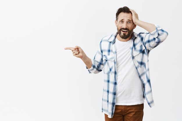 Homme d'âge mûr barbu confus et choqué posant