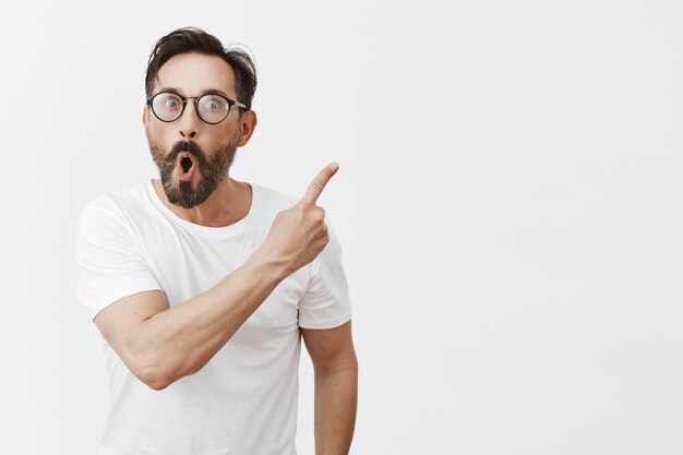 Homme d'âge mûr barbu gai avec des lunettes posant