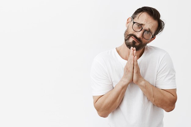 Homme d'âge mûr barbu sombre et collant avec des lunettes posant