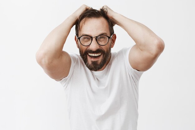 Homme d'âge mûr barbu surpris et étonné avec des lunettes posant