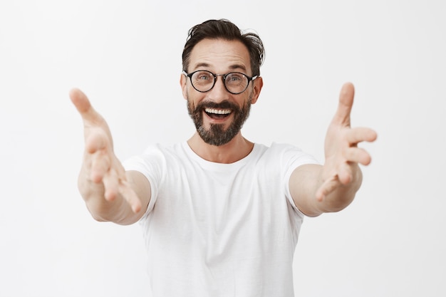 Homme d'âge mûr barbu surpris et heureux avec des lunettes posant