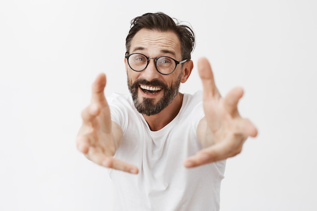 Homme d'âge mûr barbu surpris et heureux avec des lunettes posant