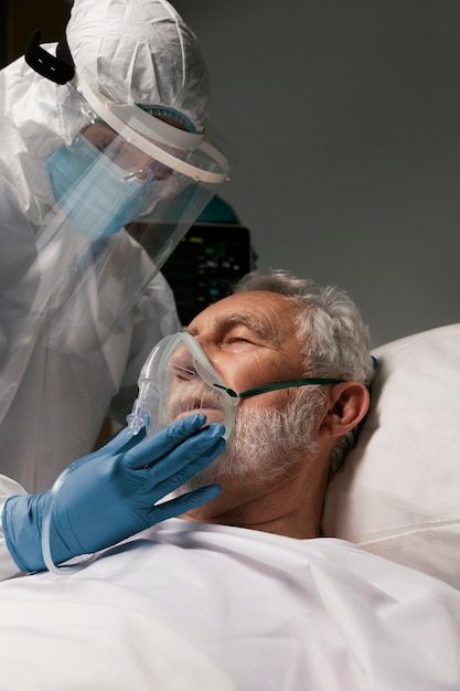 Homme âgé avec respirateur à côté des médecins