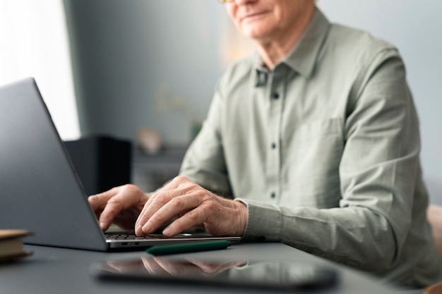Photo gratuite un homme âgé utilise un ordinateur portable assis au bureau dans le salon