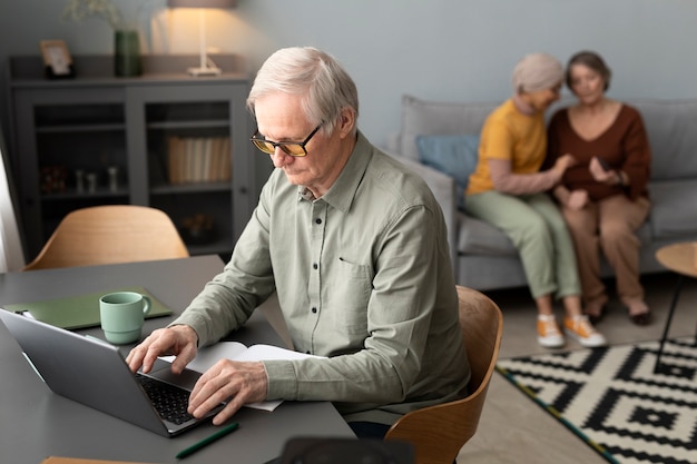 Un homme âgé utilise un ordinateur portable assis au bureau dans le salon