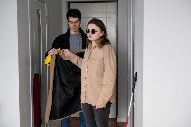 Homme aidant une femme aveugle à mettre son manteau