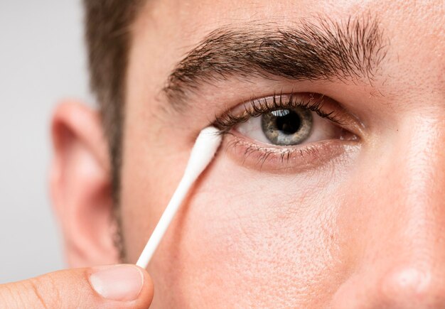 L'homme à l'aide d'un bâton d'oreille pour nettoyer ses yeux