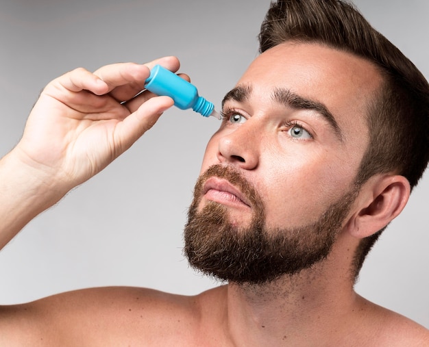 Homme à l'aide de gouttes pour les yeux