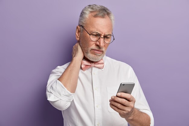 Homme aîné, dans, chemise blanche, et, rose, noeud papillon, tenue, téléphone