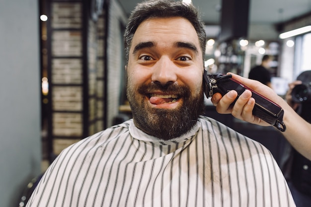 L&#39;homme a l&#39;air drôle pendant que le coiffeur travaille sur lui dans le salon de coiffure