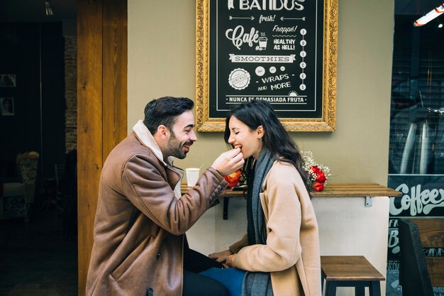 Homme alimentation femme au café en plein air