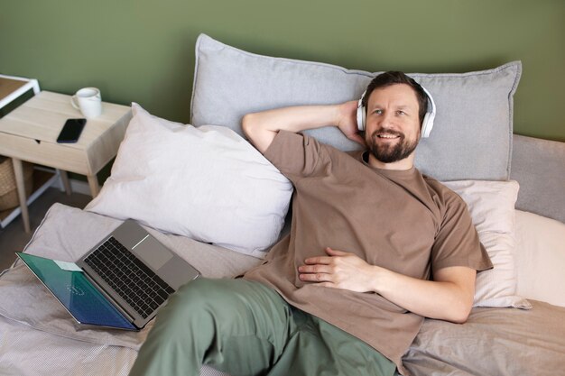 Homme allongé sur le lit en écoutant de la musique