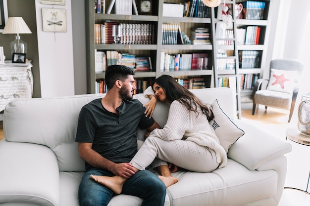 Homme amoureux et assis avec son petit ami sur un canapé blanc à la maison