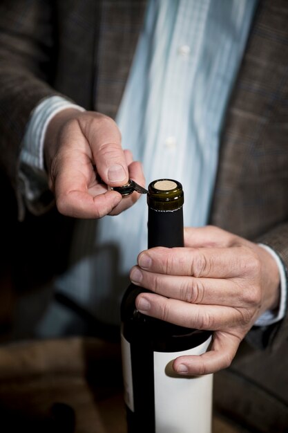 Homme à angle élevé ouvrant une bouteille de vin