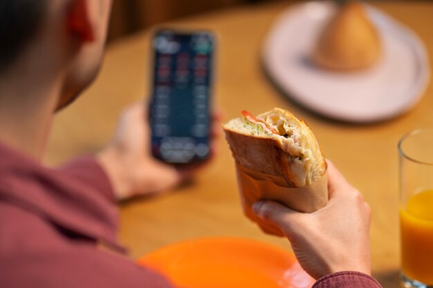 Homme à l'angle élevé avec un sandwich enveloppé en papier