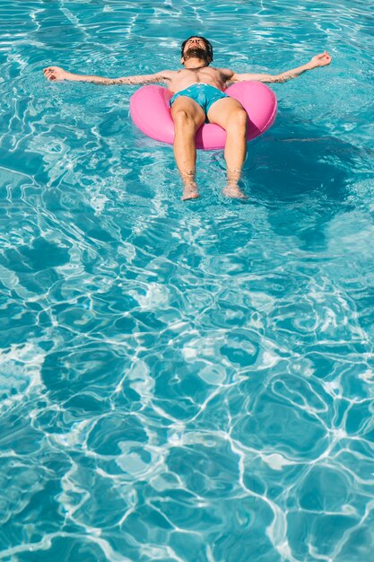 Homme sur anneau gonflable en piscine