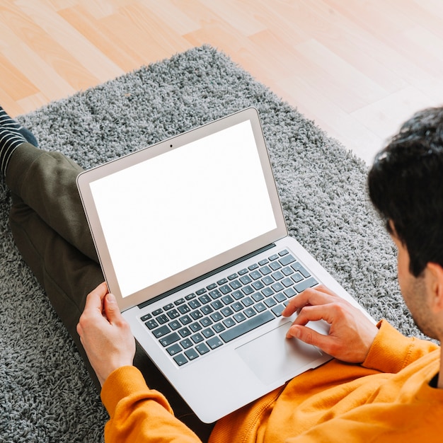 Homme anonyme en utilisant un ordinateur portable sur le tapis