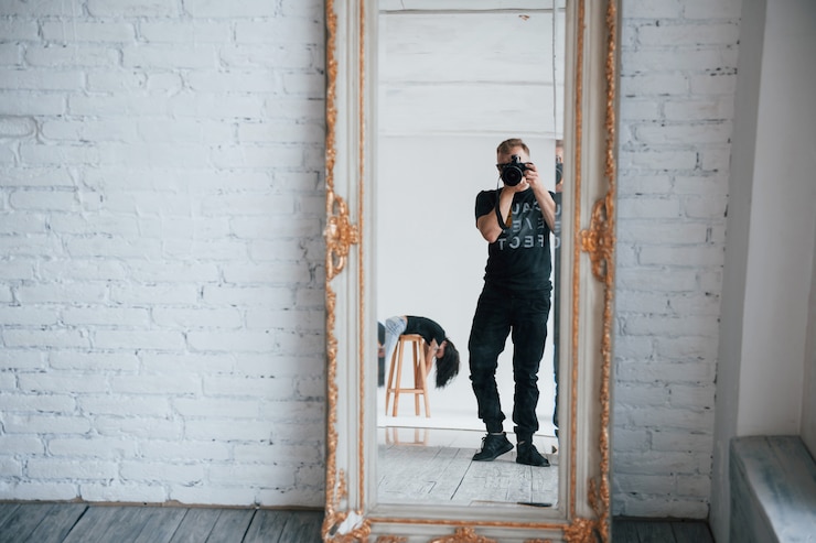 Photo gratuit homme avec appareil photo prenant une photo dans le miroir vintage. fille s'amuse derrière