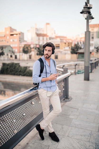 Photo gratuite homme appuyé sur une balustrade en écoutant de la musique