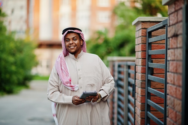 Photo gratuite homme arabe du moyen-orient posé dans la rue contre un bâtiment moderne avec une tablette à portée de main